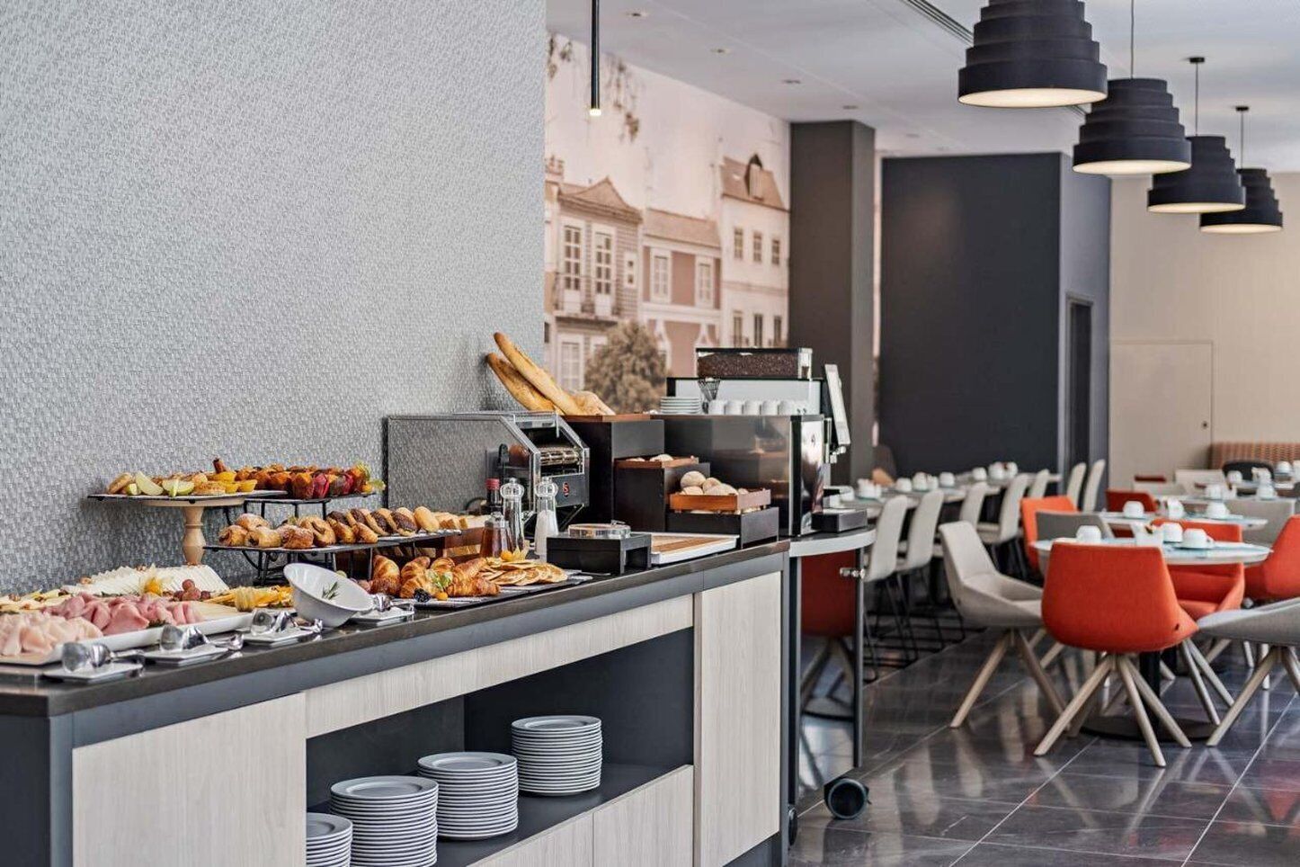A buffet area with various food items and a coffee machine. There are tables and chairs arranged for dining.