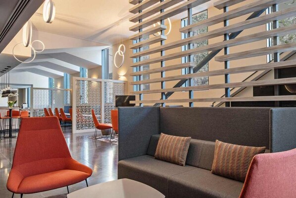 A modern interior with a sectional sofa, orange chairs, and a wooden slatted partition.