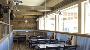 A restaurant interior with wooden walls, large windows, and multiple tables and chairs. - Newcastle Lodge and Convention Center (Newcastle)