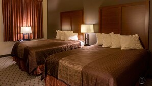 A hotel room with two beds, each with a headboard, a bedside table with a lamp, and a window with curtains. - Newcastle Lodge and Convention Center (Newcastle)