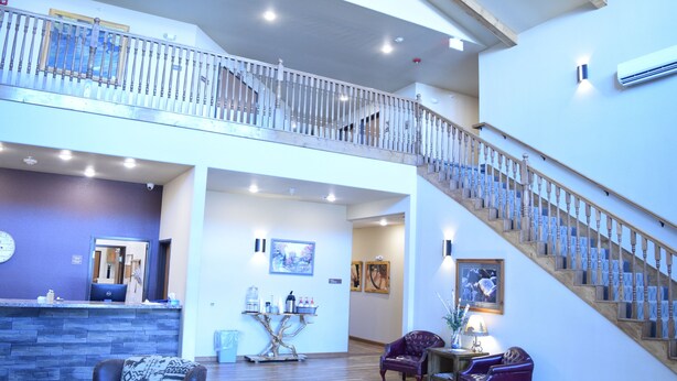 A spacious lobby with a wooden staircase, a reception desk, and comfortable seating areas. - Newcastle Lodge and Convention Center (Newcastle)