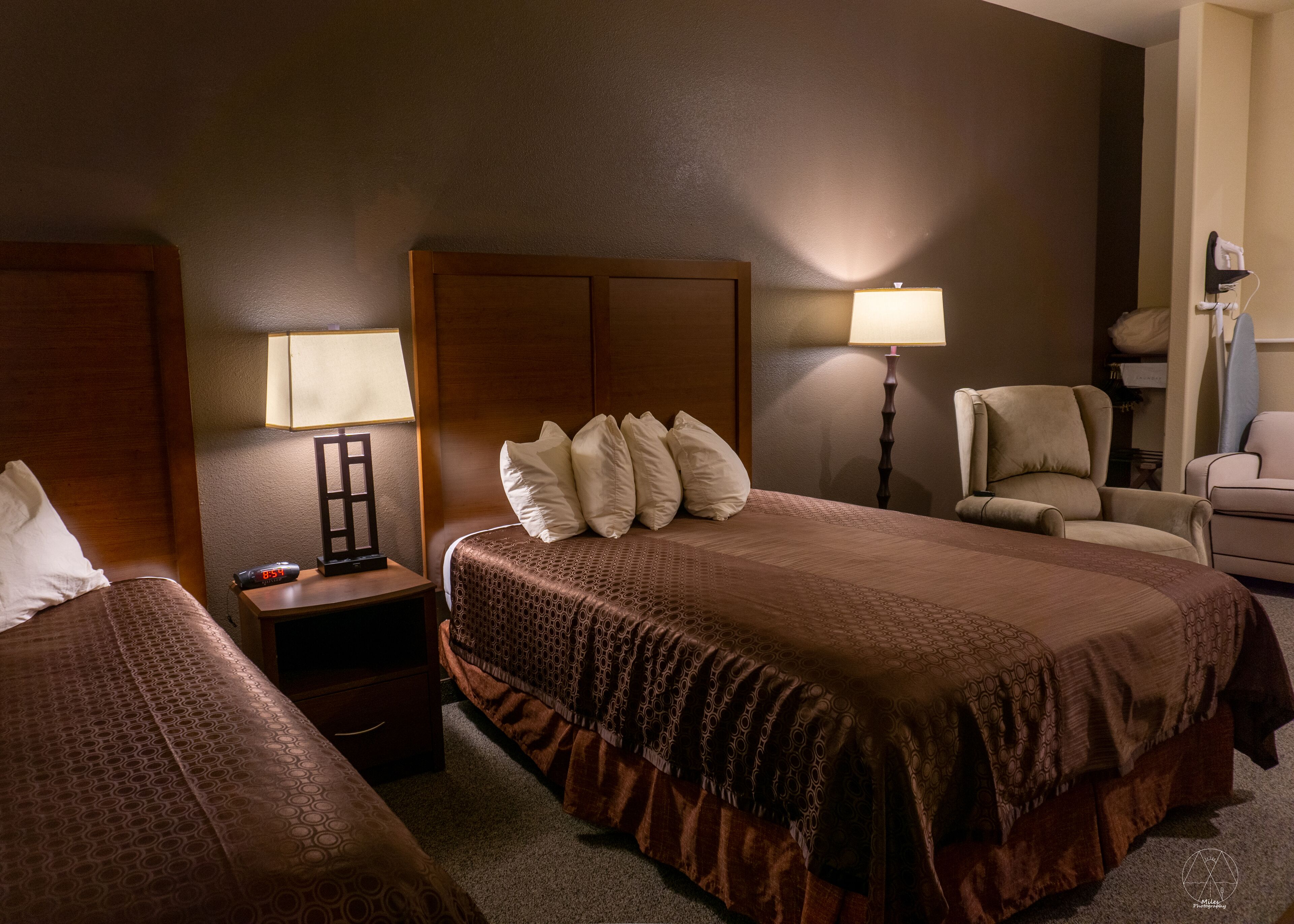 A hotel room with a large bed, two bedside tables, a chair, and a lamp.