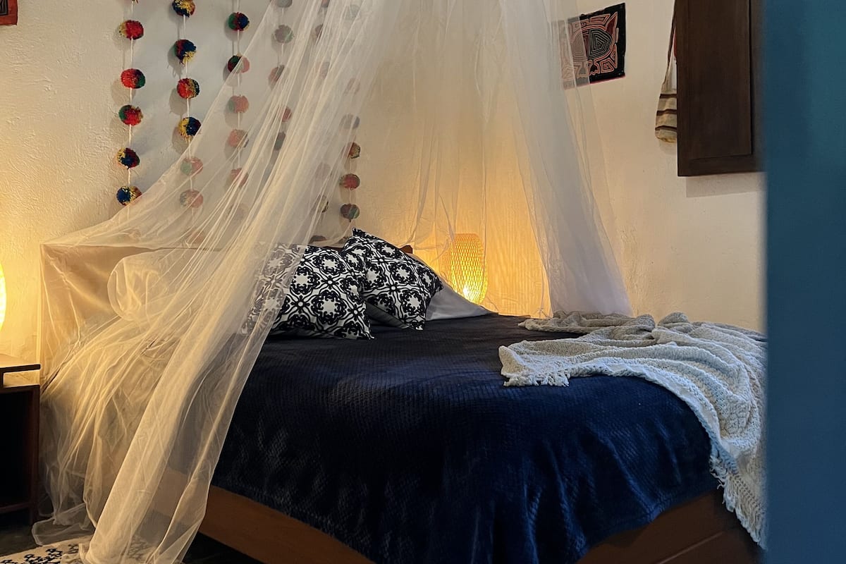 A bed with a canopy, a patterned rug, and a wall with decorative items.