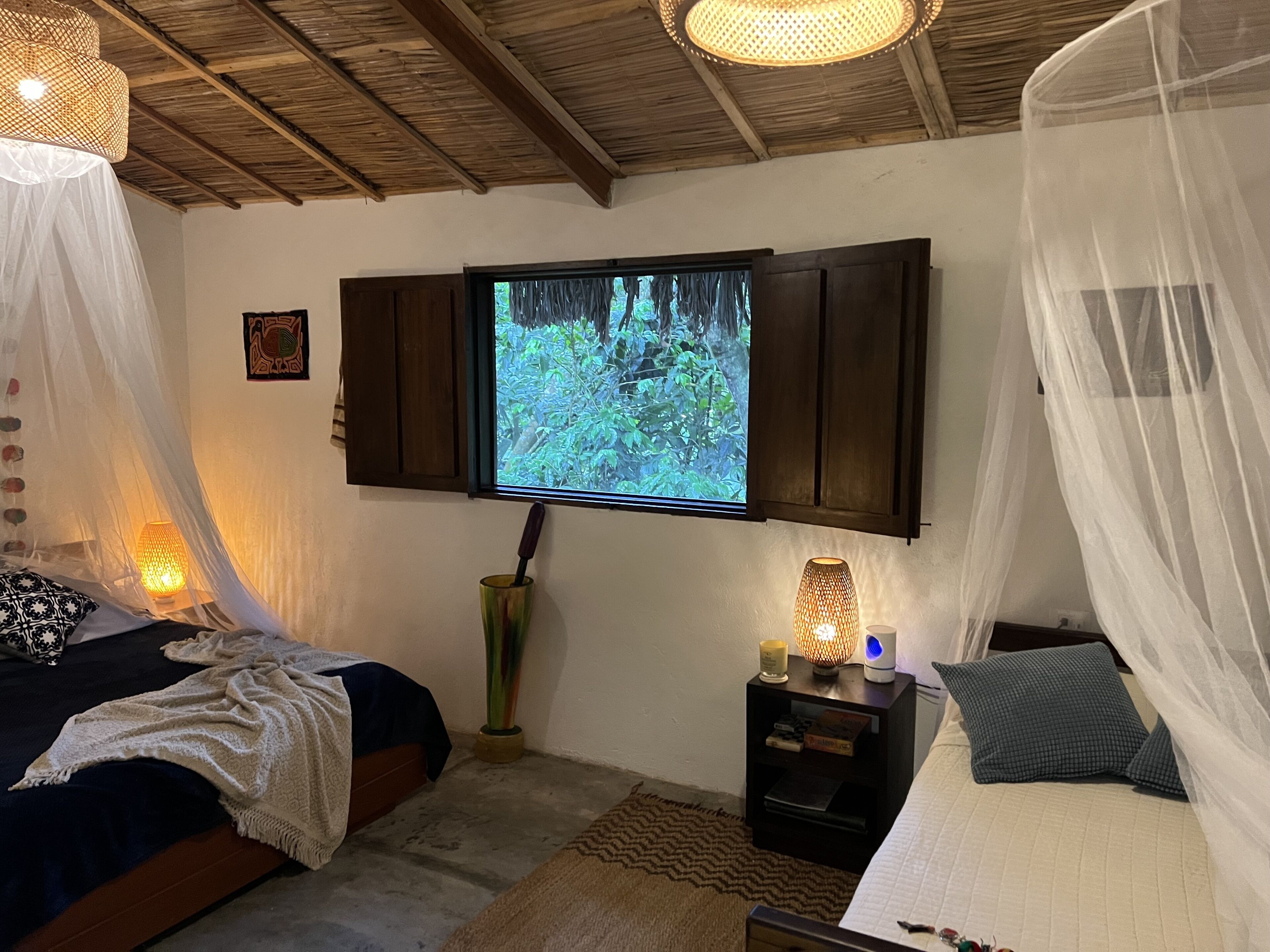 A bedroom with a bed, a nightstand, a TV mounted on the wall, and a canopy bed.