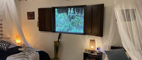 A bedroom with a bed, a nightstand, a TV mounted on the wall, and a canopy bed.