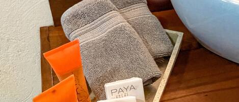 A tray with personal care items including a facial bar, a towel, and a soap bar, placed on a wooden surface near a sink.
