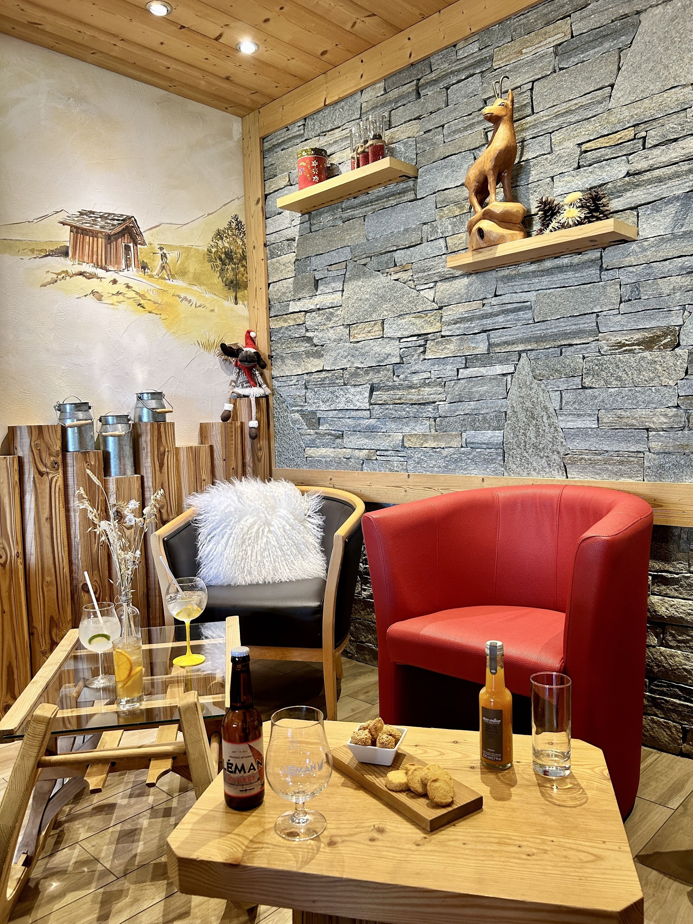 A cozy restaurant interior with a stone wall, wooden ceiling, and rustic decor.