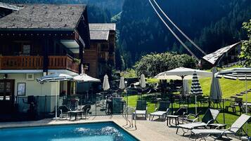 En säsongsöppen utomhuspool, parasoller och solstolar