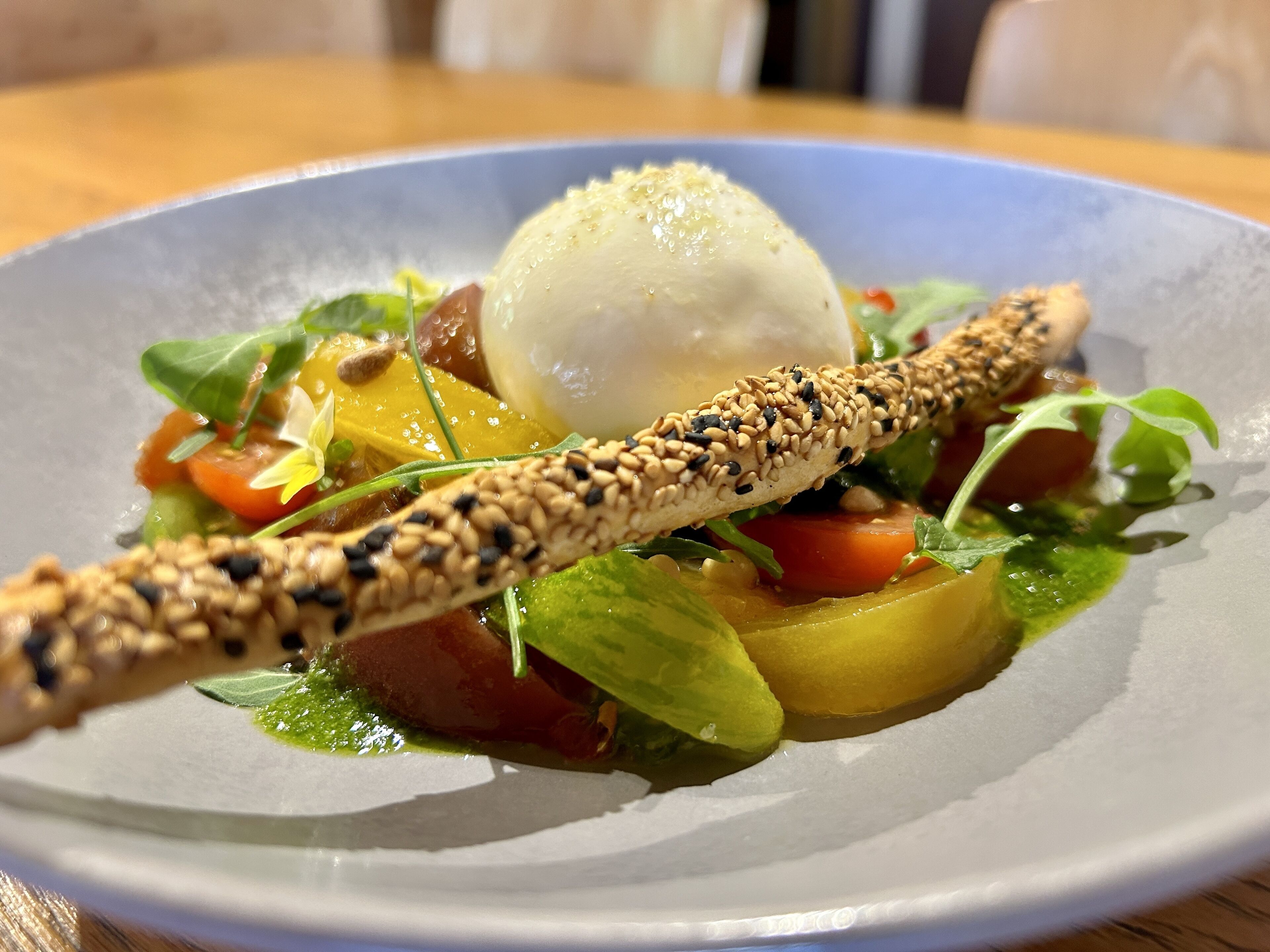 Een bord eten met een gepocheerd ei, groenten en een knapperig broodje.