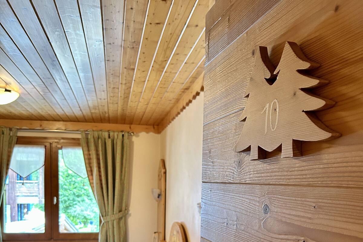 Une pièce en bois avec un lit, une horloge murale en bois et une fenêtre avec des rideaux.