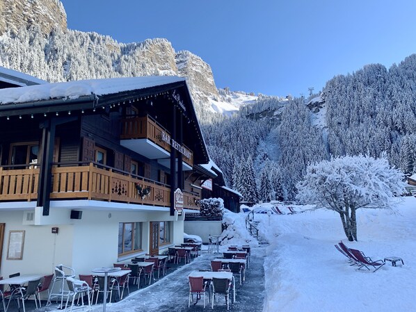 Un chalet de montagne doté d’un espace extérieur aménagé et offrant une vue sur les arbres et les montagnes enneigés.