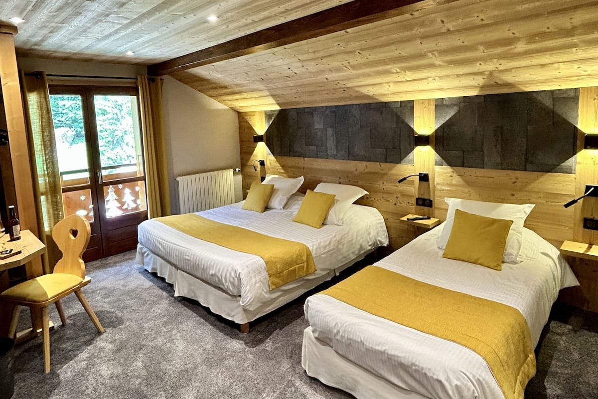 Une pièce confortable avec deux lits, un plafond en bois et un mur en pierre.