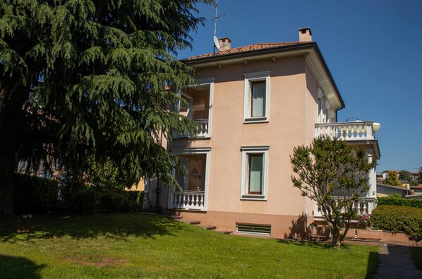 A two-story building with a balcony on the second floor, a satellite dish on the roof, and a well-maintained lawn in front. - B&B Villa le Rondini (Castronno)