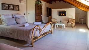 A bedroom with a wooden bed, a white wall with a fireplace, and a wooden ceiling. - B&B Villa le Rondini (Castronno)
