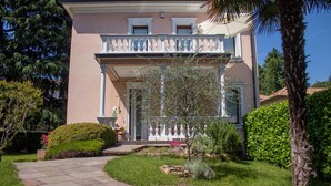 A two-story house with a covered porch, a stone pathway, and well-maintained landscaping. - B&B Villa le Rondini (Castronno)