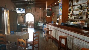 A restaurant interior with wooden furniture, a bar area, and a tiled wall with a patterned design. - Hostal Breñaverde (Gaucin)