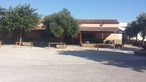 A building with a tiled roof and a covered outdoor area with benches. - Hostal Breñaverde (Gaucin)
