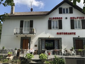 Un bâtiment blanc avec une enseigne indiquant « ALBERGO DELFINO RISTORANTE » et un balcon doté d’une balustrade en métal.