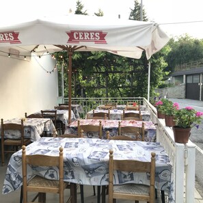 Un café en plein air avec des tables recouvertes de nappes à motifs et des chaises en bois.