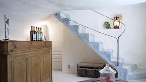 A modern interior with a wooden bar, a glass jar on a bench, and a staircase with a light fixture. - La Ferme les Eybrachas (Réauville)