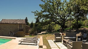 A poolside area with lounge chairs and a stone building. - La Ferme les Eybrachas (Réauville)