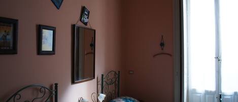 A bedroom with a bed, dresser, and a window with blinds.