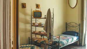 A room with a bunk bed, a small television, a mirror, and a patterned floor. - Casa Verdi (Catania)