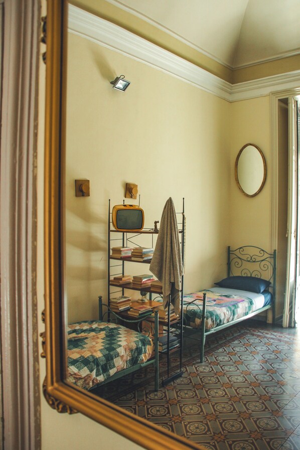 A room with a bunk bed, a small television, a mirror, and a patterned floor. - Casa Verdi (Catania)