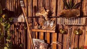 A bamboo wall with shelves holding decorative items, a guitar, and a framed picture. - Casa Verdi (Catania)