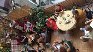 A group of people seated around a round table outdoors, engaged in conversation and eating. - Casa Verdi (Catania)