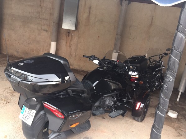 Una motocicleta estacionada en un espacio cubierto con piso de concreto y un poste de metal.