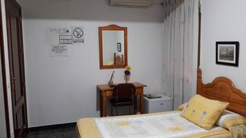 Una camera da letto con un letto, una scrivania, una sedia, uno specchio e un quadro appeso al muro.