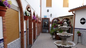 Un patio estrecho con una fuente central, arcos de ladrillo y macetas con plantas.