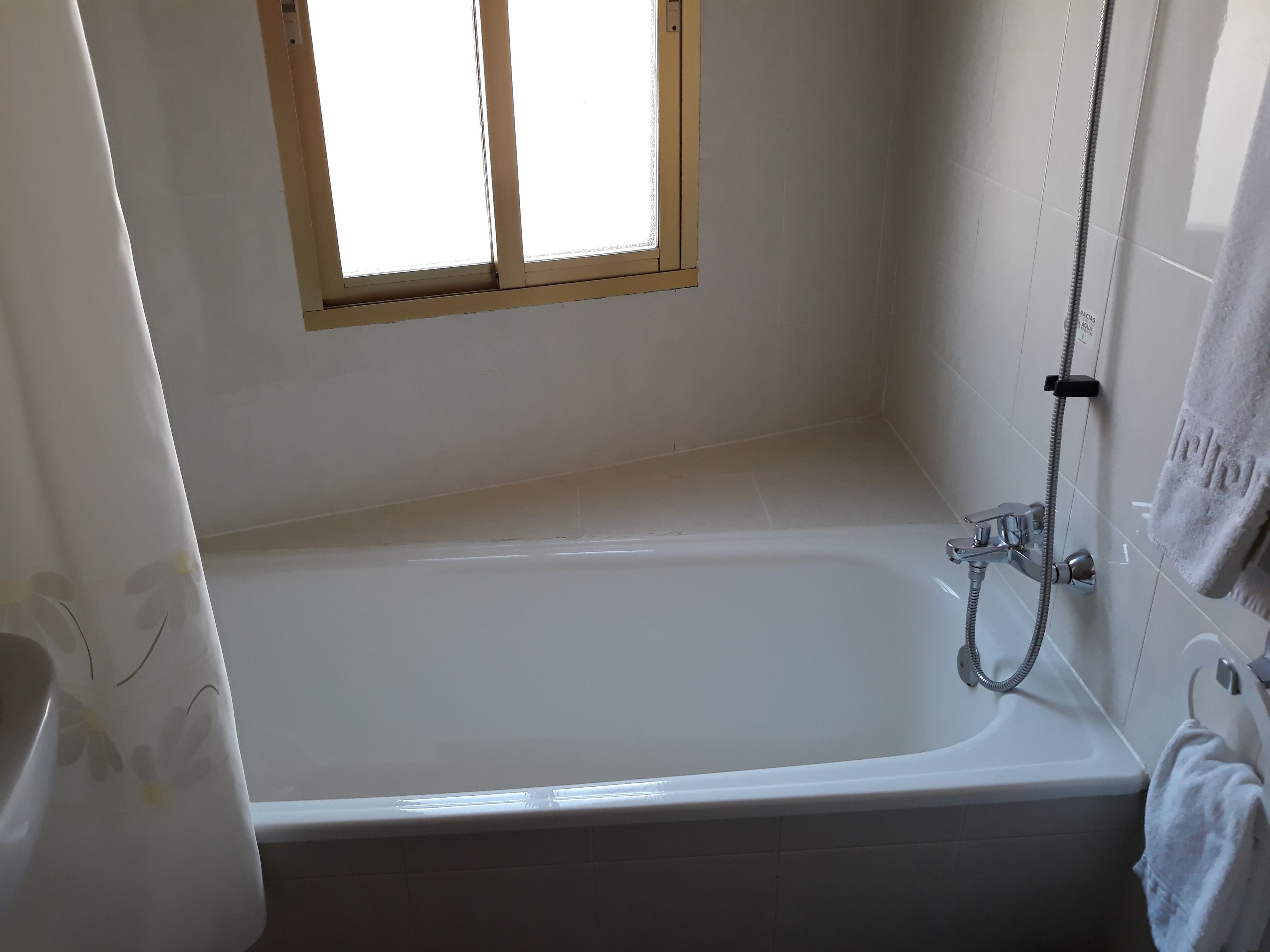 Un baño con bañera, ducha y ventana.
