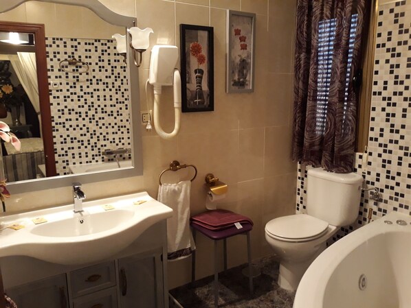A bathroom with a sink, toilet, and bathtub. There are towels and a small table with a vase.