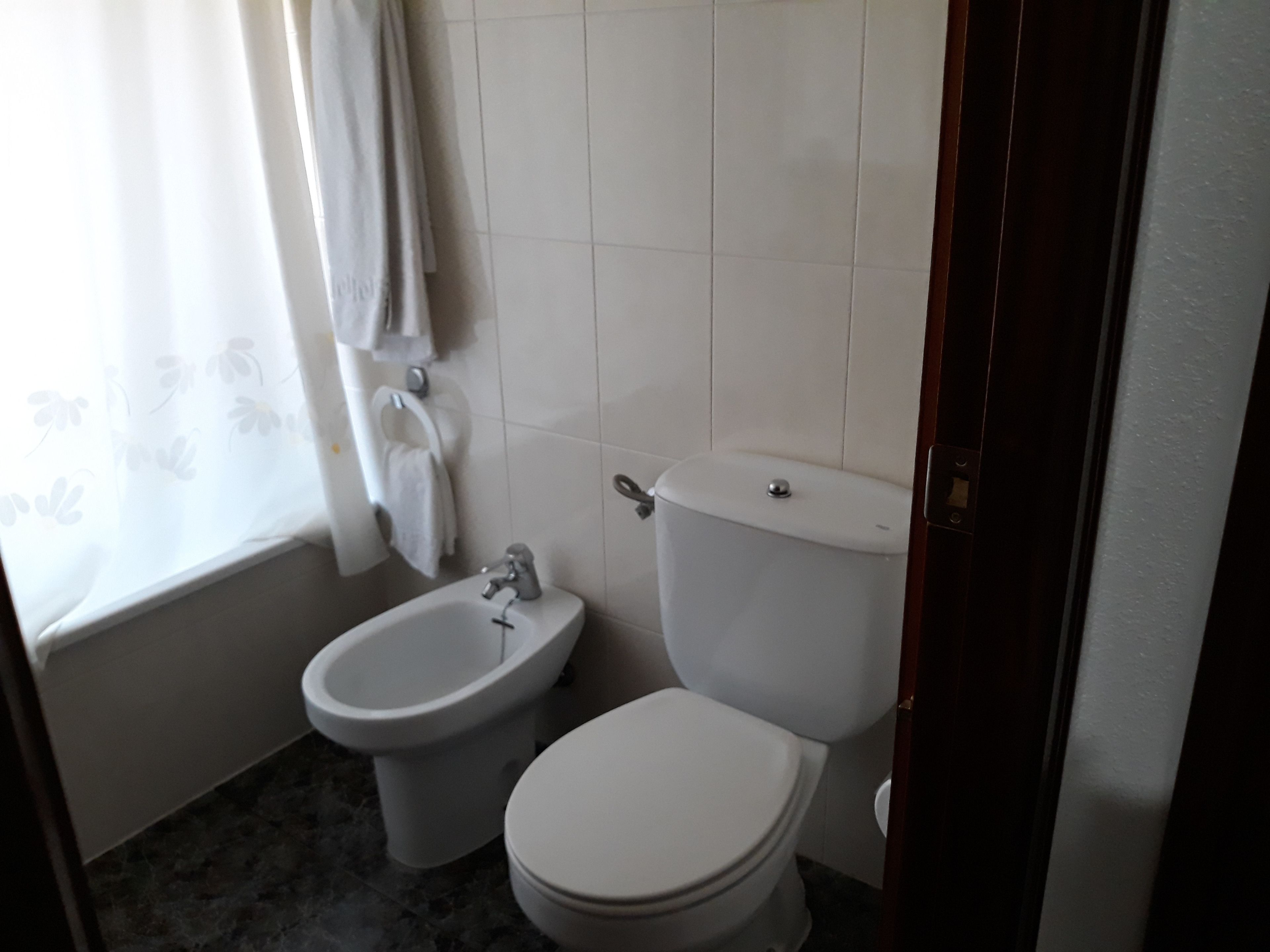 Une petite salle de bain avec des toilettes, un bidet et un rideau de douche.