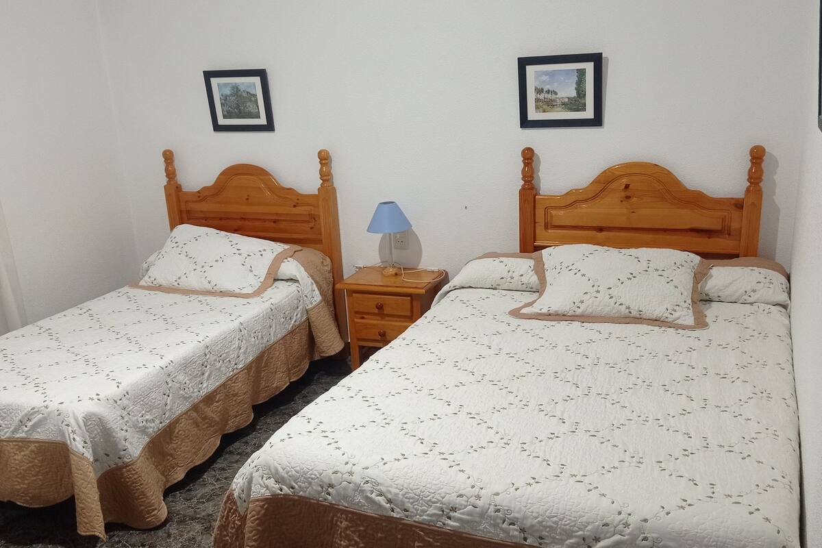 A room with two wooden beds, each with a matching headboard and footboard. There is a nightstand with a lamp between the beds.