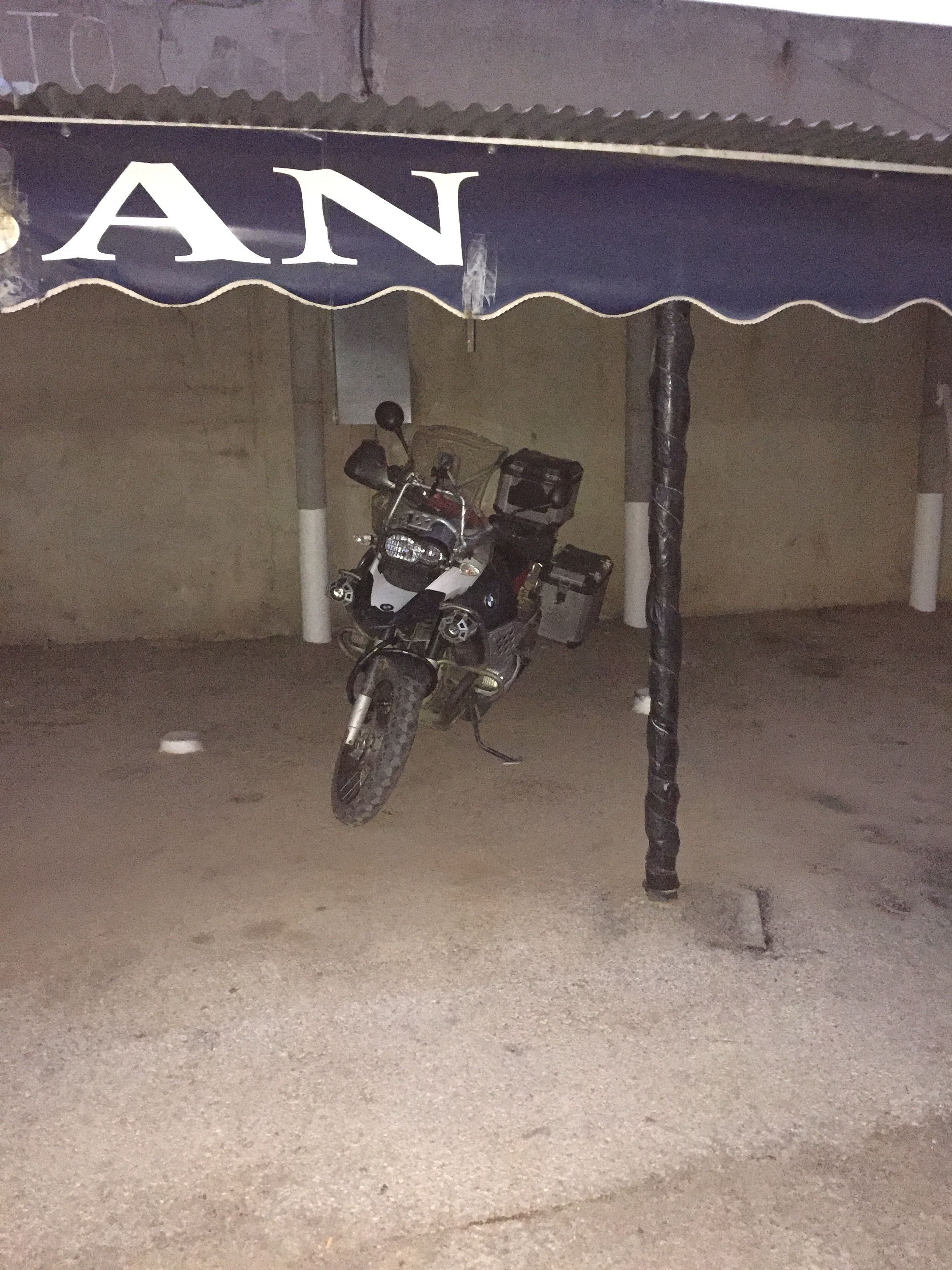 Una motocicleta estacionada bajo una estructura cubierta con un letrero que dice "AN".