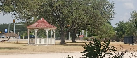 A gazebo with a red roof, surrounded by trees and open space.