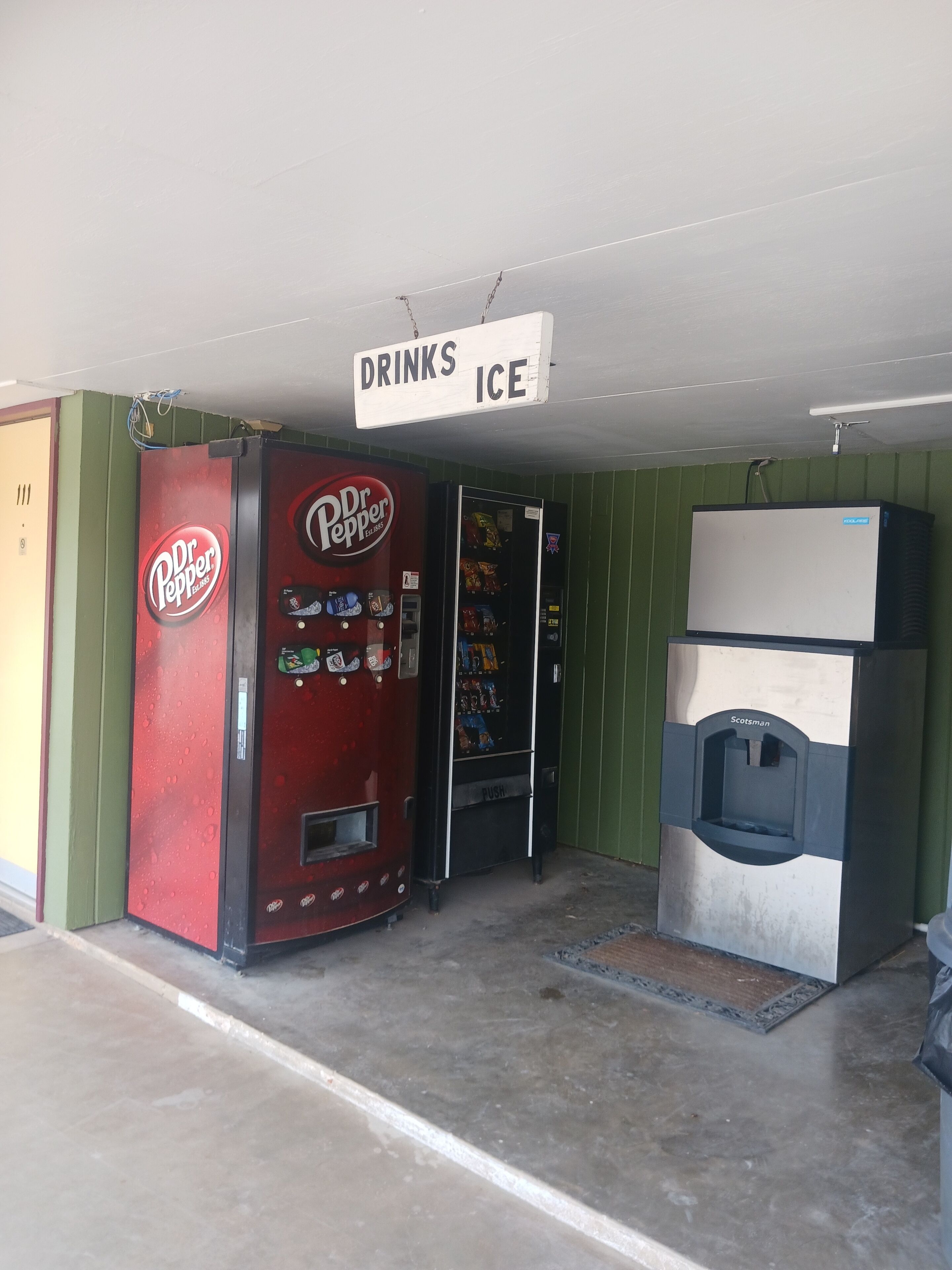 Una macchina distributrice di Dr. Pepper e un erogatore di ghiaccio Scotman in una stanza con pareti verdi.