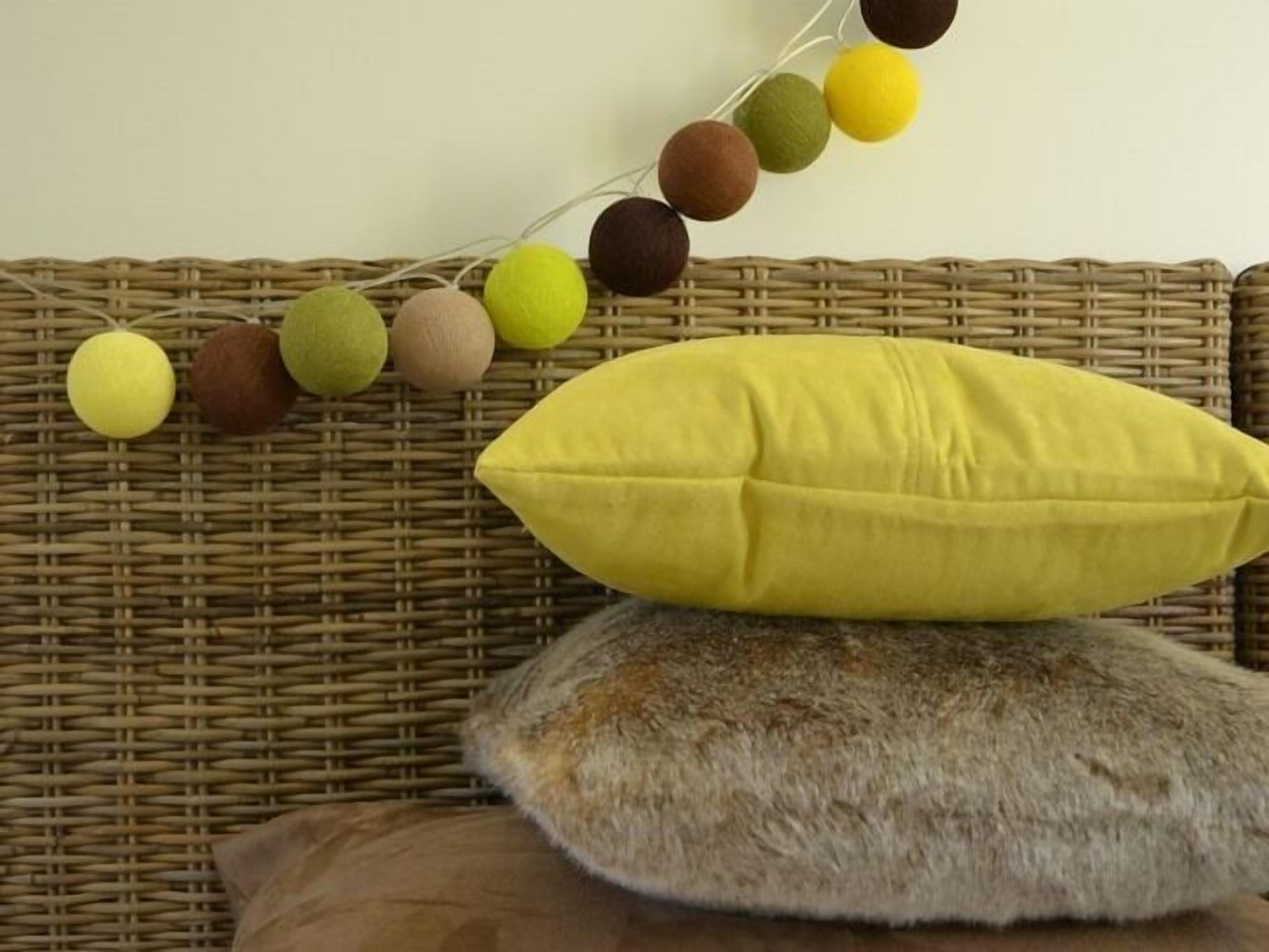 Un canapé en osier avec un coussin jaune et un coussin marron.
