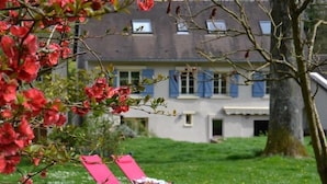 A building with a garden, two pink chairs, and a tree. - Chambres D'hôtes Villa de Vienne-en-arthies (Vienne-en-Arthies)