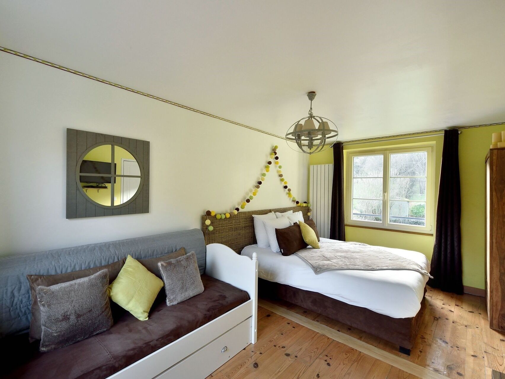 Un dormitorio con cama, sofá, espejo y ventana.