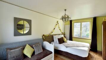 Un dormitorio con cama, sofá, espejo y ventana.