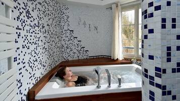 Ein Badezimmer mit mosaikbesetzter Wand, einer Badewanne und einem Fenster mit Blick auf Bäume.