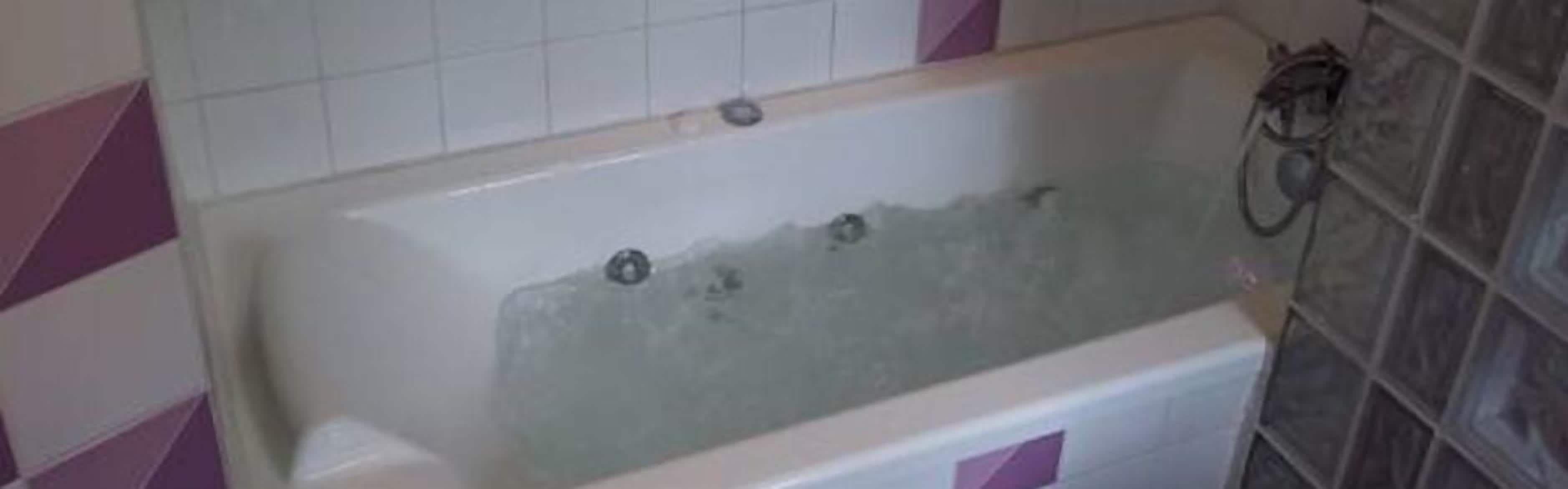 Ein Badezimmer mit einer Badewanne, einer Dusche und gefliesten Wänden.