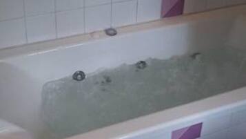 Ein Badezimmer mit einer Badewanne, einer Dusche und gefliesten Wänden.