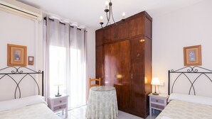 Habitación de hotel con dos camas, un armario de madera, una mesa redonda y una silla.