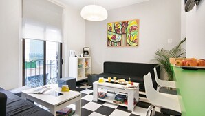 Una sala de estar moderna con suelo a cuadros blanco y negro, un sofá negro, una mesa de centro blanca y un cuadro abstracto y colorido en la pared.