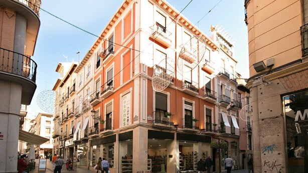Una calle con edificios, tiendas y gente.